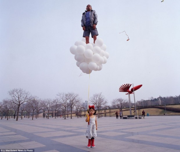 Going with the float: Artist Li Wei's daughter seems unconcerned that her father is standing on top of her balloons